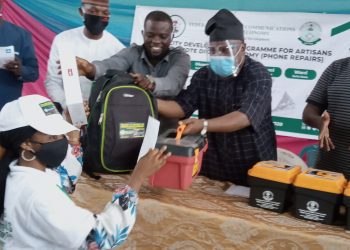 caption. Chairman Senate Committee on Land Transport Senator Buhari Abdulfatai joined by representative of NITDA DG Alhaji Inuwa Abdulahi to present an mobile tablets, tool kit and statrt up cash to one of the participants at the closing ceremony of training on Digital economy for Artisans in Oyo organized by NITDA