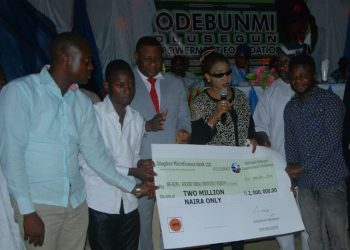 Hon debunmi and his wife presenting a cheque of  2million naira to re[presentatives of the student in tertiary institution in his constituency