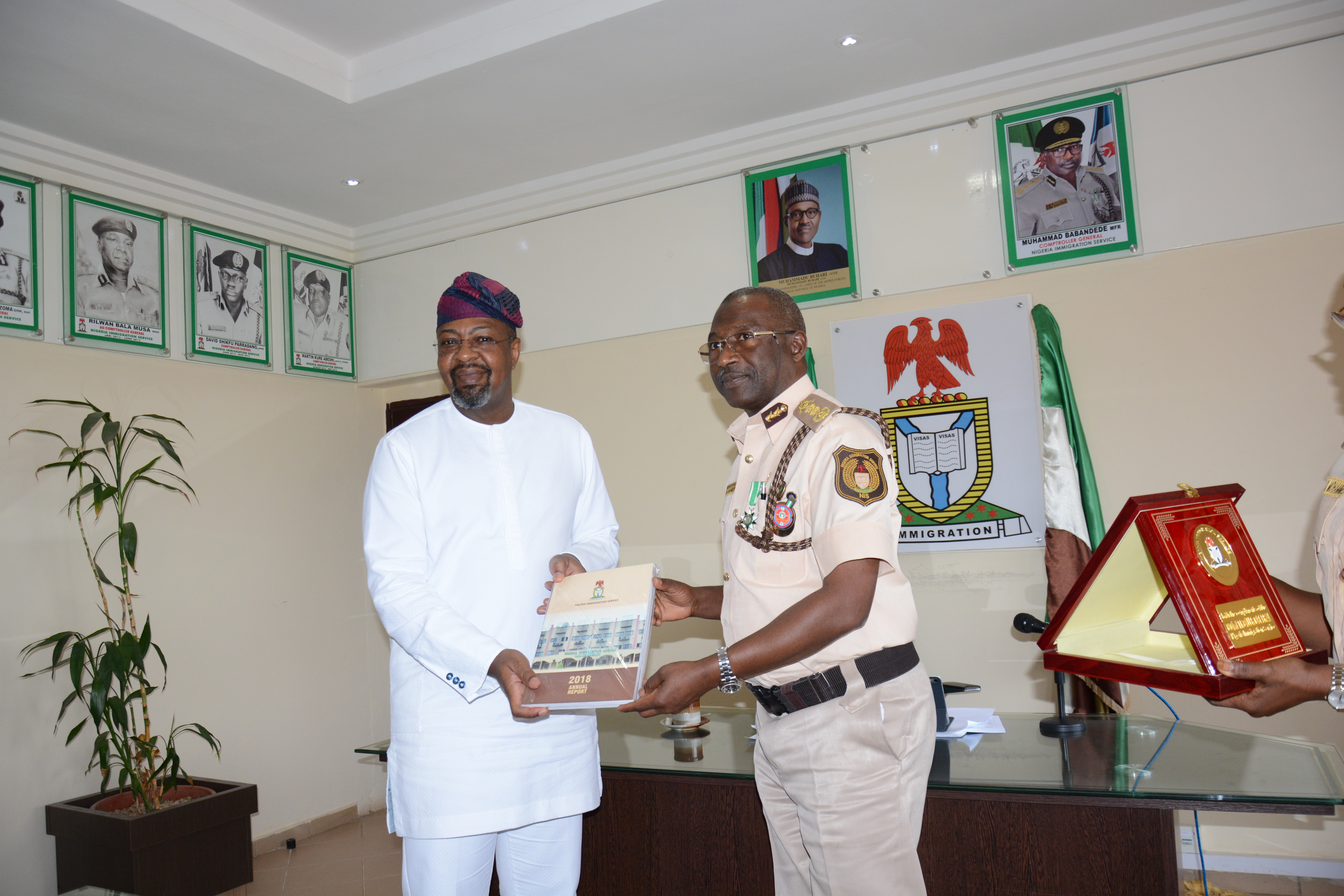 The Director General, Nigerian Tourism Development Corporation (NTDC) , Mr. Folorunsho  Coker (Left)  receiving the 2018 annual report  from  the Comptroller General ,  Nigeria Immigration Service (NIS) , Muhammad Babandede, MFR  during a courtesy visit on the Comptroller General  to discuss ways  of collaboration and partnership on the ease of doing tourism business held  at the Immigration corporate headquarters  in Abuja recently.