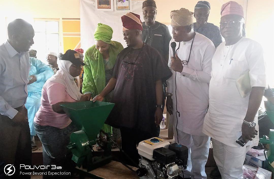 Senator Folarin presenting grinding machine to one of the beneficiaries