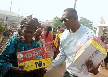 Mr Tijani Usman presenting a pack  of noodles to an aged woman