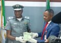 Customs’ Area Comptroller for the Command, Comptroller Mohammed Shuaibu handing over the CFA 7million exhibit to the EFCC’s Head of Investigation, Lagos Zone 2, at Idiroko, an Assistant Commander of EFCC, Oguzi Moses